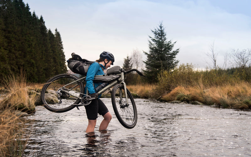 Fording a river with a gravel bike on a bikepacking adventure