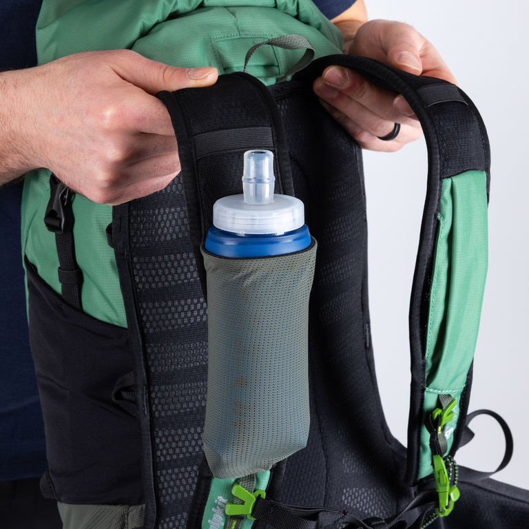 Person attaching a water bottle holder to a backpack